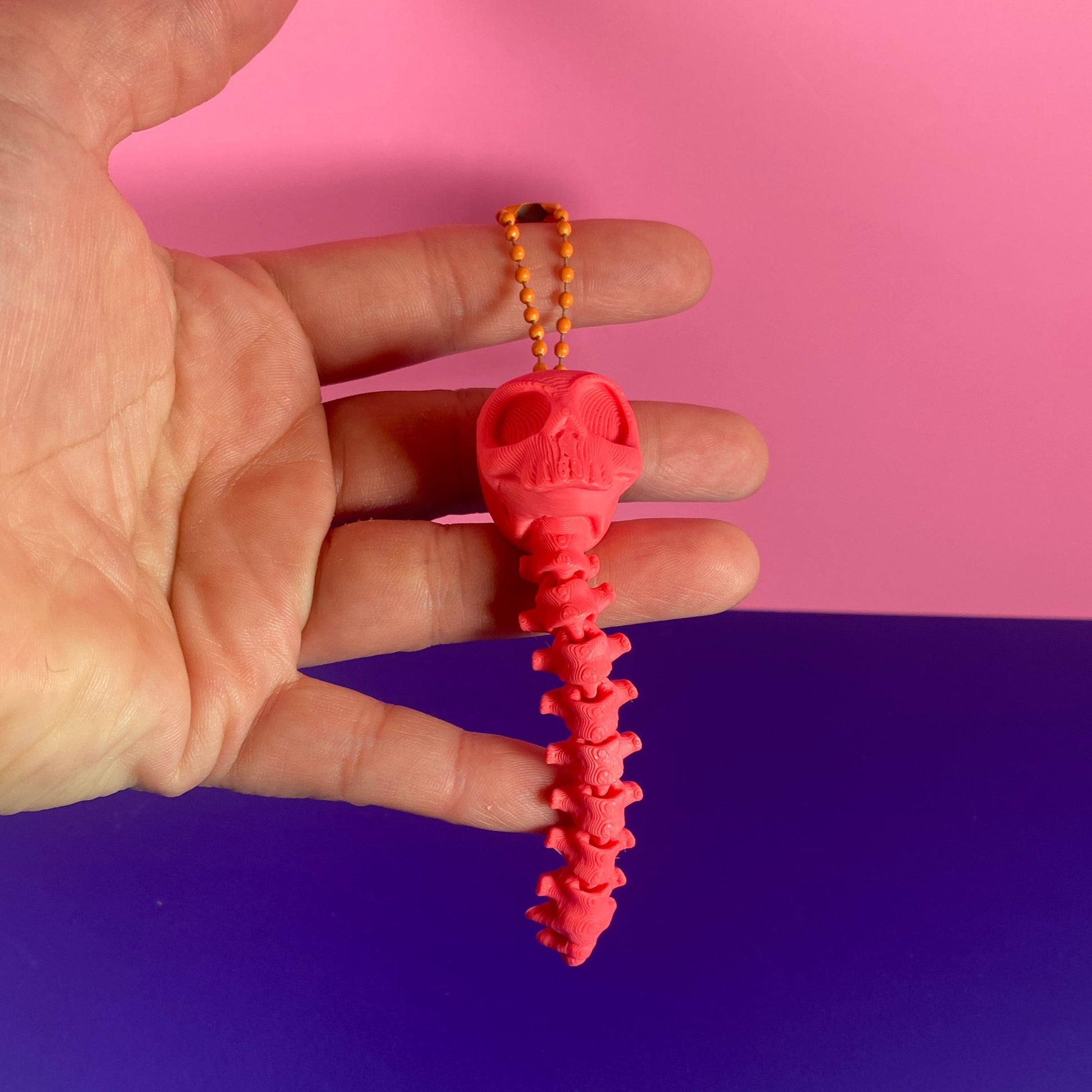 Pink textured object held between fingers against a pink and blue background
