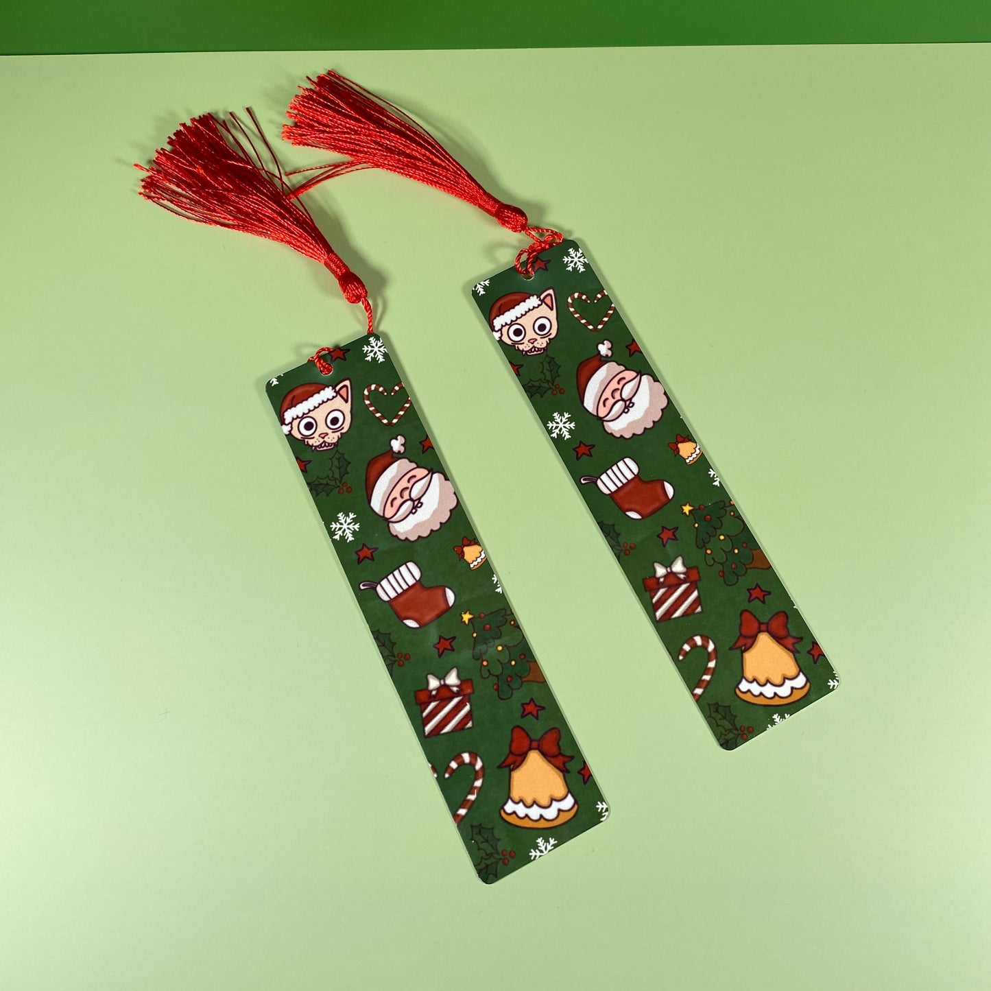 Two green bookmarks with festive patterns and red tassels on a green background