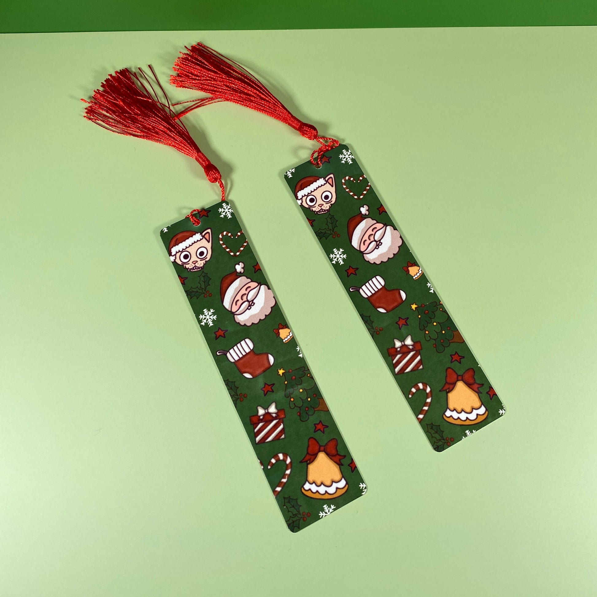 Two green bookmarks with festive patterns and red tassels on a green background